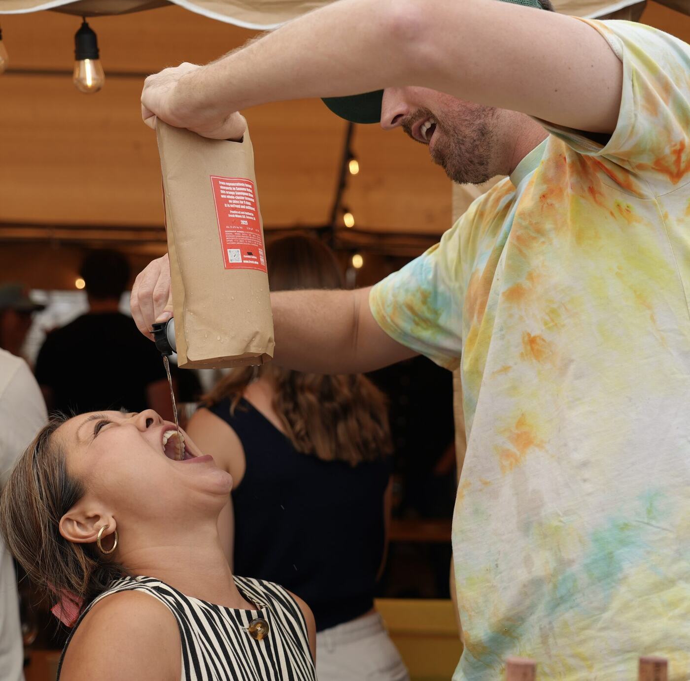 A winemaker pours straight from a bag into a guest's mouth